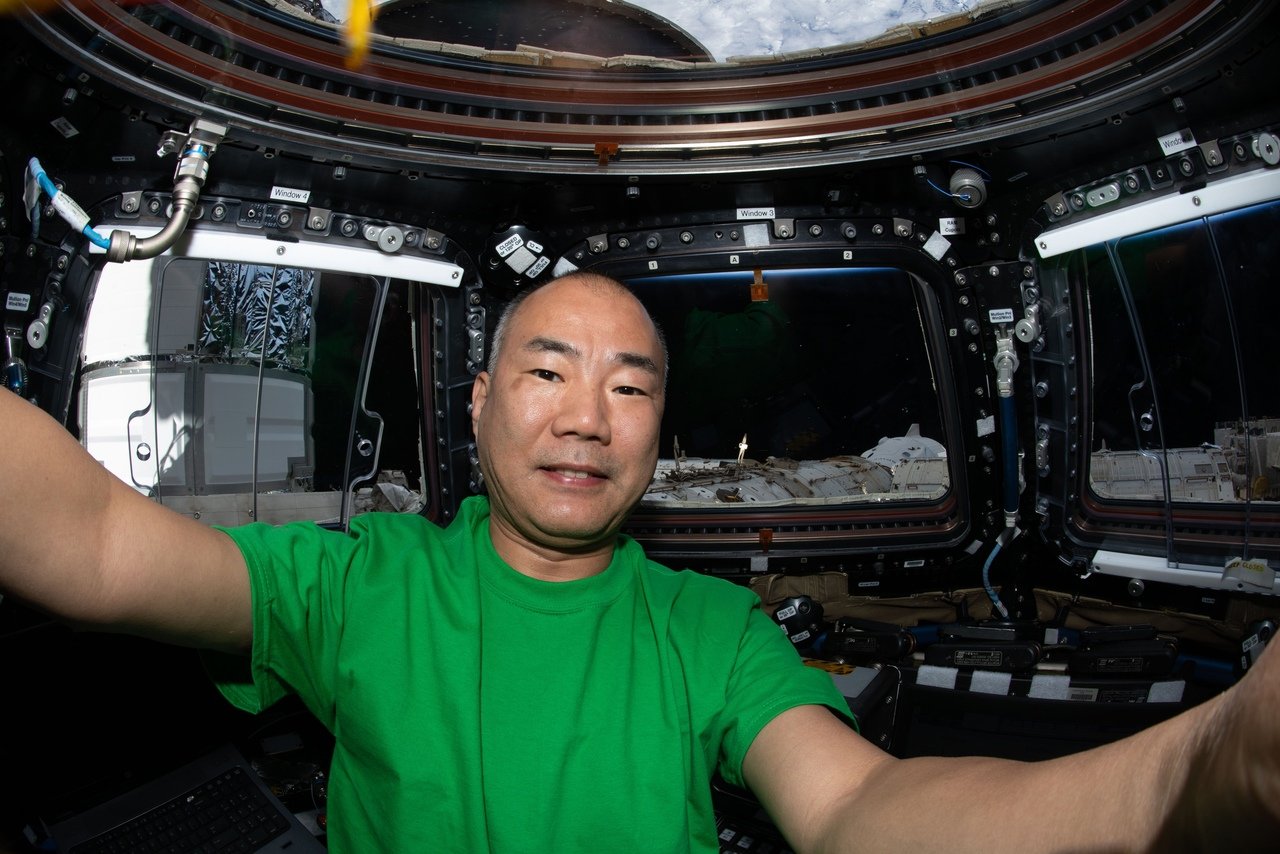 Соичи Ногучи в модуле Купол на МКС. Можно увидеть корабль Crew Dragon пришвартованный к станции